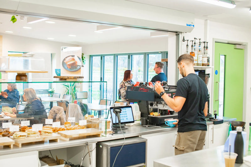 People in a bakery or cafe with customers and staff at the counter.1